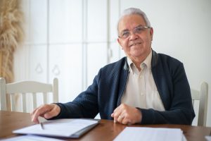 Homme senior consultant les conditions de son assurance appareil auditif à domicile.