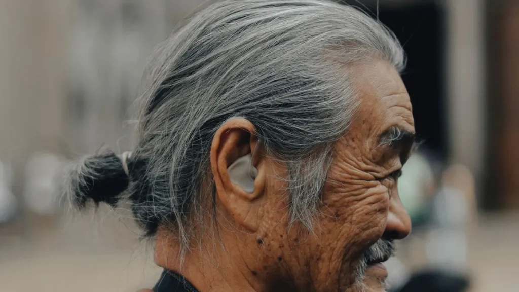 Homme senior de profil portant un appareil auditif intra-auriculaire beige, forme courante en classe 1.