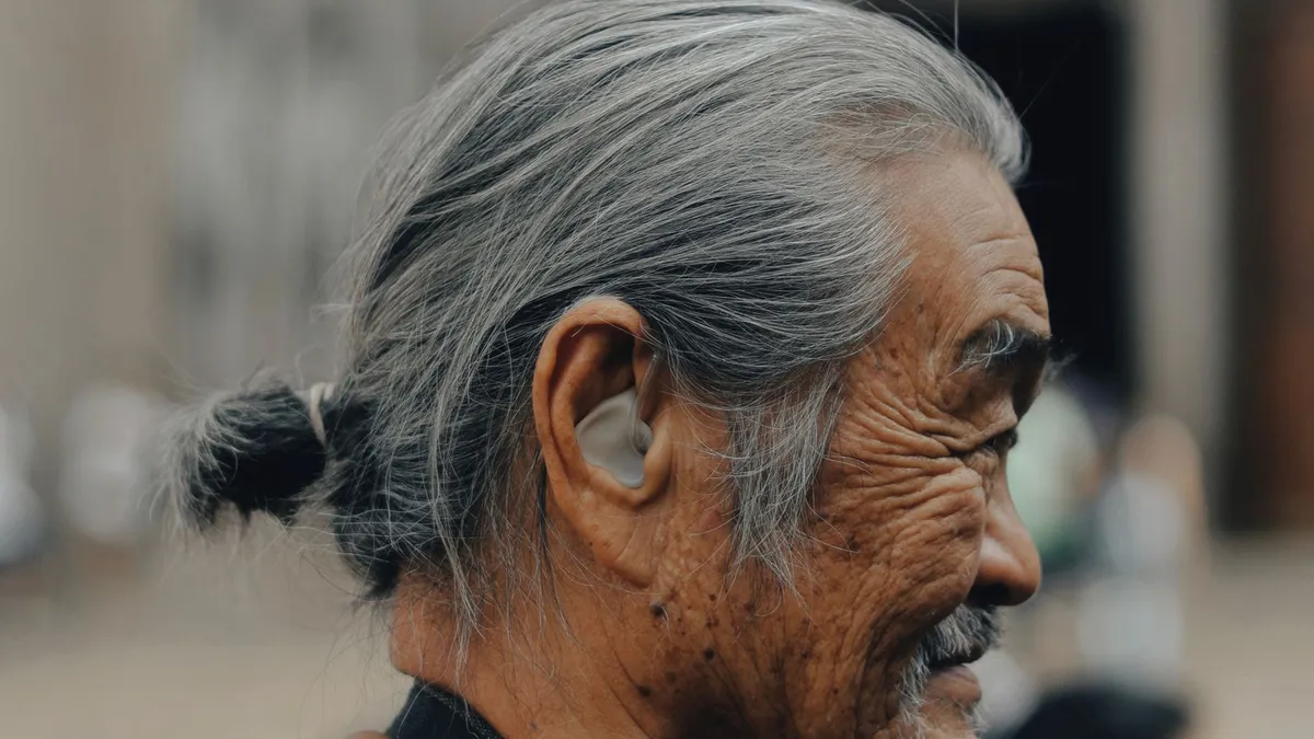 Homme senior de profil portant un appareil auditif intra-auriculaire beige, forme courante en classe 1.