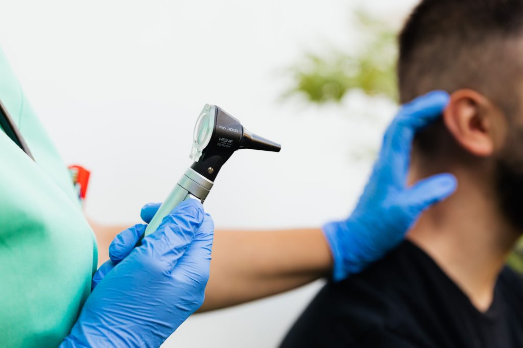 Audioprothésiste examinant l'oreille d'un patient à l'otoscope pour un acouphène pulsatile