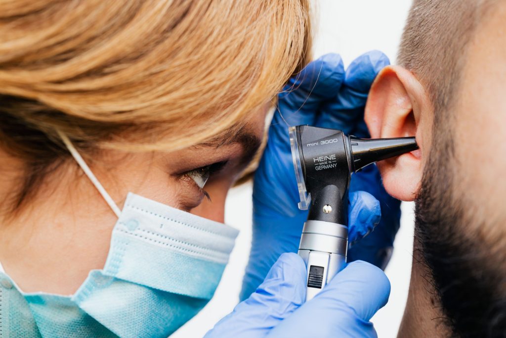 Audioprothésiste examinant l'oreille d'un patient à l'otoscope pour un appareil auditif de classe 1