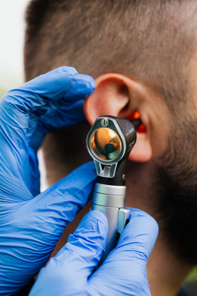 Audioprothésiste examinant l'oreille d'un patient à l'otoscope pour diagnostiquer une hypoacousie